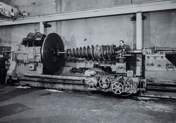 1985: Big Bertha, a giant lathe, bought at auction in Tacoma in 1985. It takes 2 – 7.5 ton cranes to lift her out of her concrete home. We move it into 5930 with a 30-foot length tow bed, and use it for 11-12 years on big projects, like this 1996 West Point Treatment Plant centrifuge. The outside blades measure 40 – 50 inches in diameter.